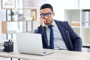 Businessman in glasses, thinking by his computer.